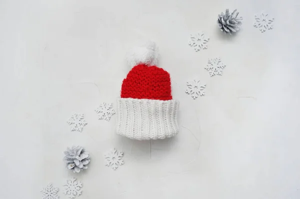 Santa czerwony kapelusz na drewnianym tle. Boże Narodzenie tło z szyszki i płatki śniegu — Zdjęcie stockowe