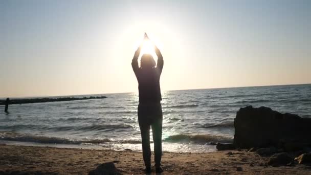 Νεαρή γυναίκα κάνει γιόγκα στην παραλία το πρωί. Βίντεο 4k — Αρχείο Βίντεο