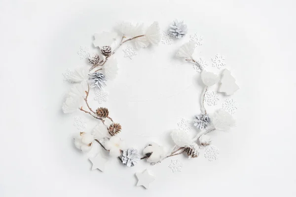 Couronne de Noël faite de flocons de neige en bois, de fleurs de coton, de cônes de pin et de pompons de fleurs blanches. Fond blanc. Couché plat, vue du dessus — Photo