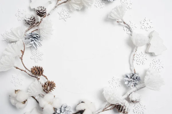 Corona de Navidad hecha de copos de nieve de madera, flores de algodón, conos de pino y pompones de flores blancas. Fondo blanco. Piso tendido, vista superior — Foto de Stock
