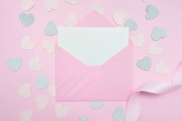 Mock up de envelope rosa em branco com ovelhas brancas de papel. Cartão de saudação com corações de confete de prata e fita na mesa rosa de madeira no dia dos namorados ou da mãe — Fotografia de Stock