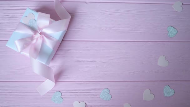 선물 상자에 리본 과 콘 페티가 있는 핑크 색 나무 배경에 글을 넣을 자리가 있는 하트 형태의 선물 상자. 발렌틴의 날, 어머니 날, 또는 생일에 대한 비디오의 움직임. 위에서 본 HD — 비디오