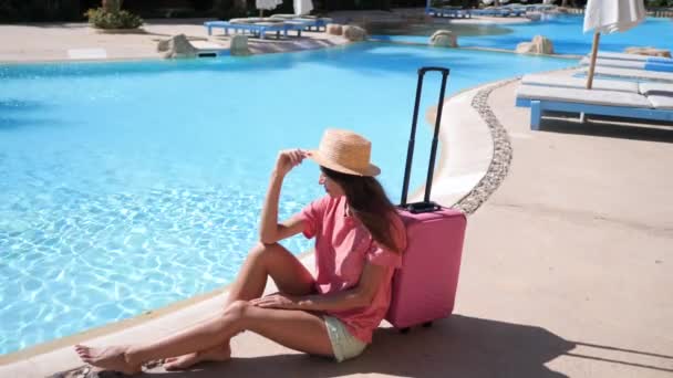 Mujer joven con estuche rosa se sienta cerca de la piscina en el hotel. Concepto de vacaciones de viaje. Vídeo HD en ProRes 1920x1080 — Vídeos de Stock