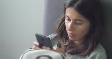 Bağımlı genç bir kadının internette akıllı telefon kullanarak sohbet edip sörf yaptığını gösteren 4K 'lık bir video. Gün ışığı. Gezici bağımlılık ve uykusuzluk