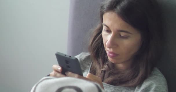 Vidéo large 4K d'une jeune femme accro discutant et surfant sur Internet à l'aide d'un téléphone intelligent. Lumière du jour. Dépendance mobile et insomnie — Video