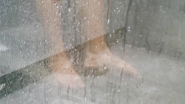 Woman is standing in the shower and washes herself with a shower gel. Close up of legs and feet. Motion 4k video, 3840x2160 footage — Stockvideo