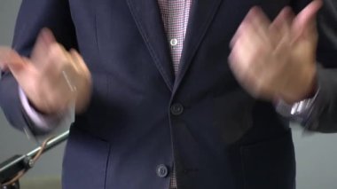 Konuşma yaparken ve bir şeyleri açıklarken bir erkek konuşmacının ellerini kapat. Sığ alan derinliği, seçici odaklanma. Tam Hd video hareketi, 1920x1080