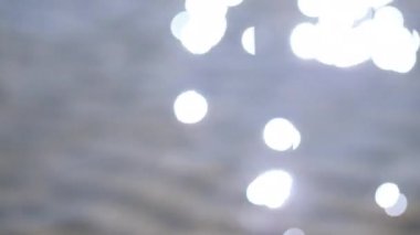 Denizde mavi ve ışıl ışıl Bokeh ışığı. Bokeh 'le güneş ışığına yansıyor. Deniz yüzeyinden yansıyan güneş parıltılarıyla dolu bir su yüzeyinin odaksız görüntüsü.