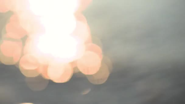 Bleu et étincelant fond clair Bokeh dans la mer. réfléchissant à la lumière du soleil avec un bokeh. Vue déconcentrée d'une surface d'eau avec un beau bokeh de rayons de soleil qui se reflètent de la mer — Video