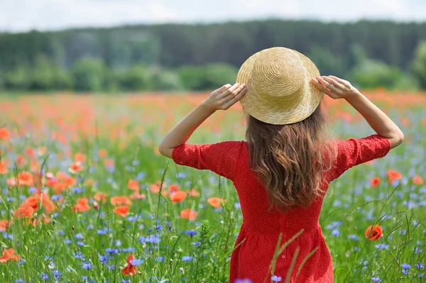 Мечтательная женщина в красном платье и шляпе на красивом травяном цветущем маковом поле. Винтажный элегантный романтический вид. Концепция прекрасного лета — стоковое фото