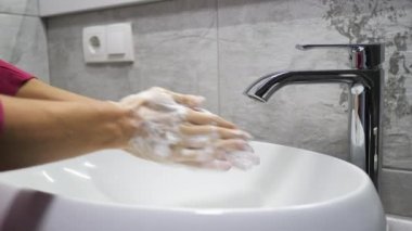 Kadın geniş çaplı Corona virüsü covid-19 'a yakalanmamak için ellerini yıkıyor. Tanınmayan kişi ellerini antibakteriyel sabunla iyice yıkıyor. 4k video gerçek zamanlı görüntü