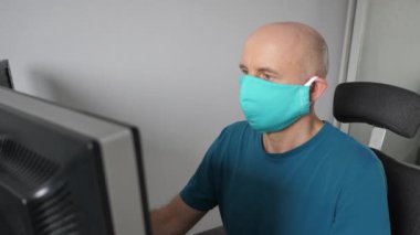 Coronavirus. Koruyucu maske takan bir adam evde çalışıyor. Koronavirüs için koruyucu maske takarak karantina. Evden çalışmak