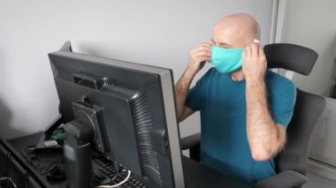 Coronavirus. Koruyucu maske takan bir adam evde çalışıyor. Koronavirüs için koruyucu maske takarak karantina. Evden çalışmak