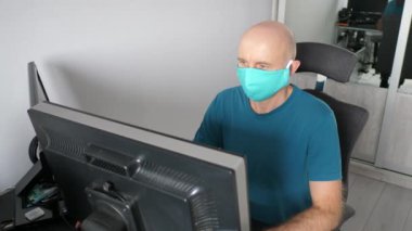 Coronavirus. Koruyucu maske takan bir adam evde çalışıyor. Koronavirüs için koruyucu maske takarak karantina. Evden çalışmak