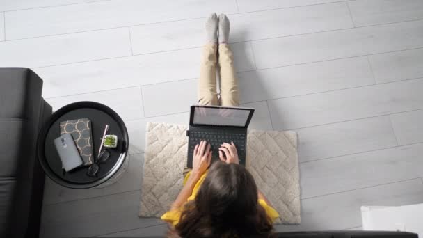 自宅のソファの近くの床に座って ラップトップコンピュータで作業する女性のフリーランスのトップビュー ラップトップで入力する女性 隔離概念はオンラインで働く — ストック動画