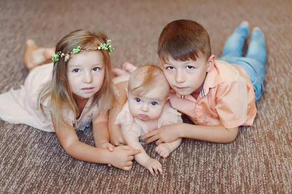 Kleine Kinder hängen zusammen und lächeln im Studio auf dem Boden. Bruder und zwei Schwestern — Stockfoto