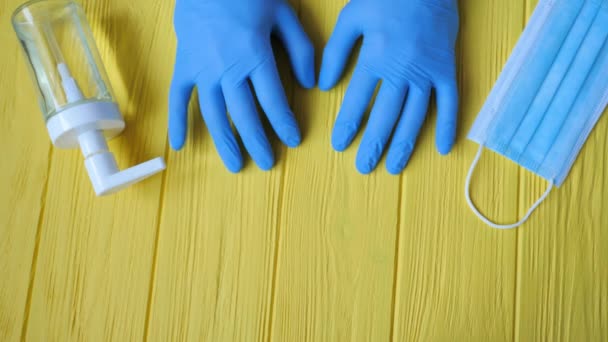 Botella desinfectante de manos en primer plano con guantes. Pide desinfección de manos. Detener el concepto de coronavirus. Mascarilla respiratoria en el fondo. Uso de gel antibacteriano para las manos durante la cuarentena — Vídeo de stock