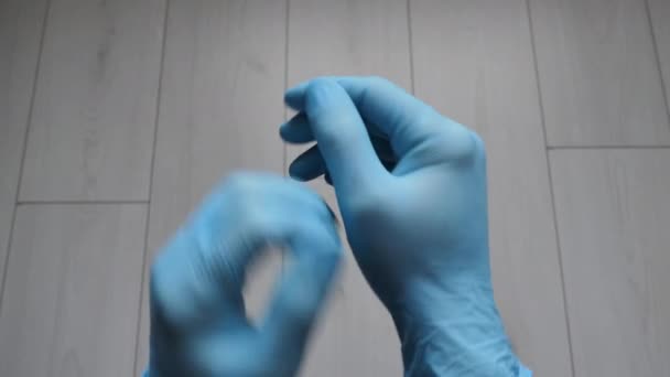 Доктор одягнув сині стерильні хірургічні рукавички на руки на червоному тлі. Крупним планом. Концепція страхування пандемії коронавірус, гігієна, захист рук, контроль вірусної інфекції — стокове відео