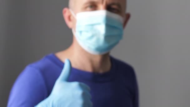 Buena medicina para el trabajo. Hombre con guantes y una máscara médica da pulgares hacia arriba y OK signo — Vídeos de Stock