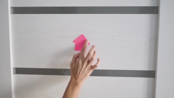 Крупным планом женские руки наклеивают розовые бумажные простыни на белые деревянные двери. Концепция дома рабочего карантина — стоковое видео