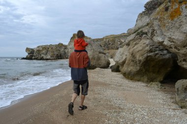 Kumsalda yürüyen bir çocuk olan bir adam. Cimea