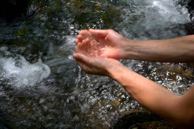 Nehirden elinde su. Bir adam elini avuç nehirden su toplar