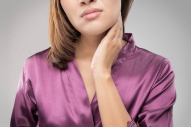 Closeup girl with sore throat touching her neck clipart