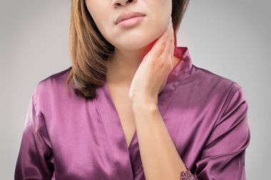 Closeup girl with sore throat touching her neck clipart