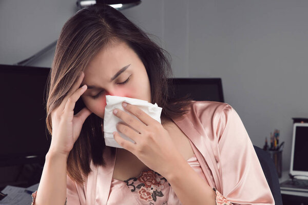 Asian women in satin nightwear feeling unwell and sneeze