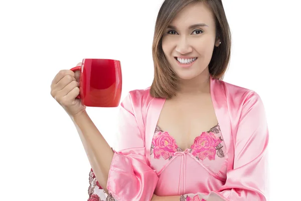 Азіатський жінка в рожевими атласними нічне тримають кавові чашки червоний — стокове фото