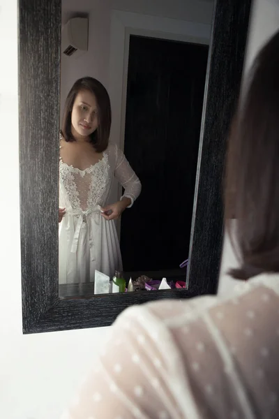 Asian woman puts on her white satin nightwear. — Stock Photo, Image