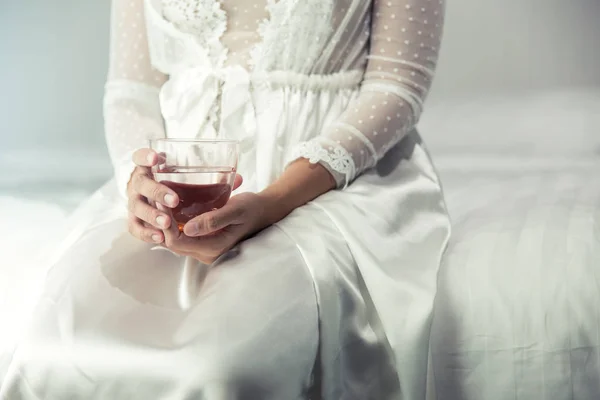 Mujer en ropa de dormir blanca mano sosteniendo un vaso de agua limpia en — Foto de Stock