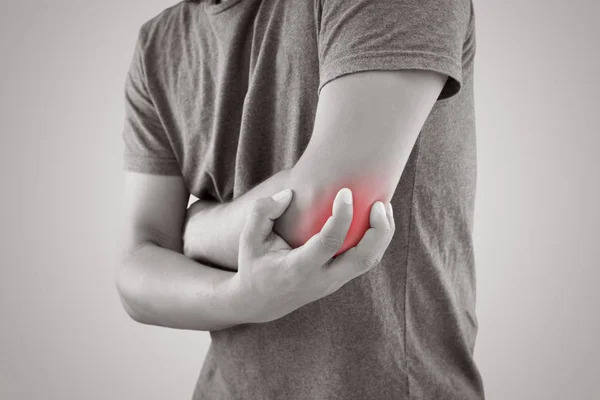 Asian man with pain in elbow against gray background — Stock Photo, Image