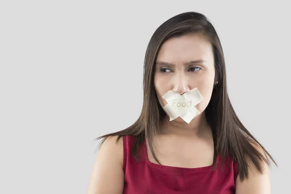 Woman with stick tape with striked through word food covering mouth — Stock Photo, Image