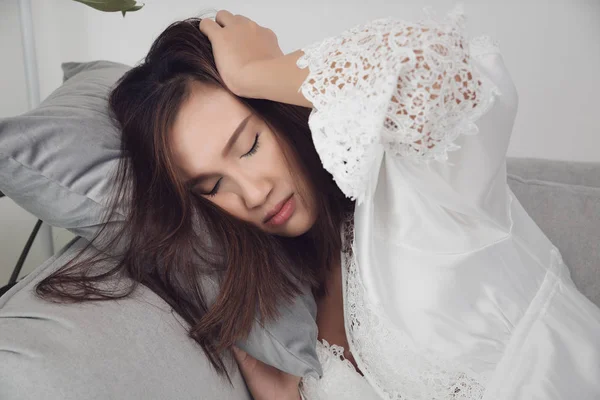 Mulheres usam camisola de cetim branco sonolência no quarto . — Fotografia de Stock