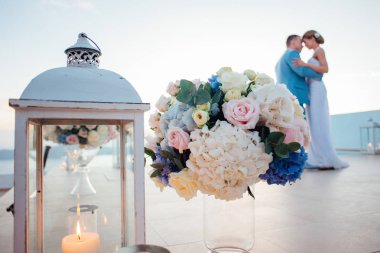 Gelin ve damat günbatımında Santorini Adası bir buket ve cam fener bir mum ile arka planda dans