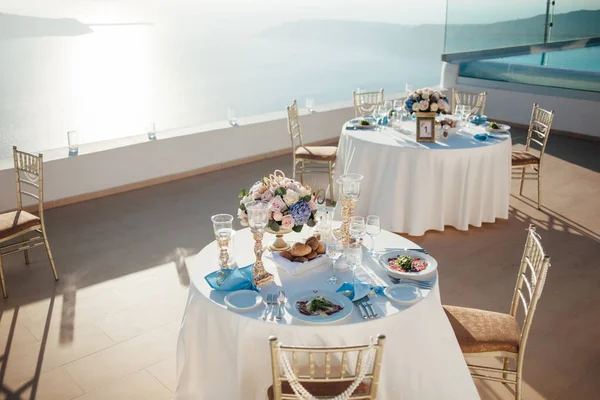 Wedding decor of tables on the island of Santorini in gold, blue and white colors at sunset