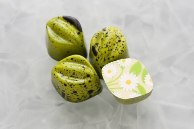 Dört el yapımı çikolata kaplama ile daisieson ile siyah damla parlayan yeşil beyaz mat cam arka plan candies
