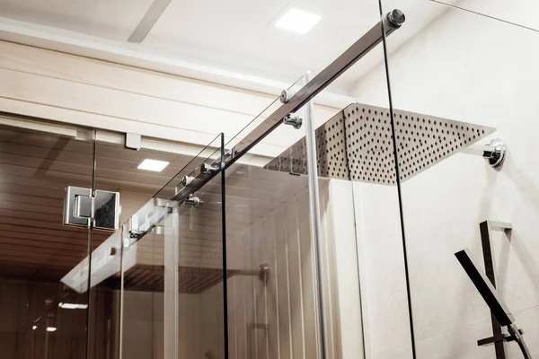Metal structure of the upper fasteners and rollers for the sliding glass door in the shower enclosure conjugated with the glass door to the sauna view in the interior
