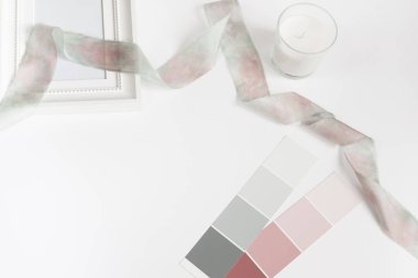 Beyaz bir mum, bir çerçeve, gri-mavi ve pembe renk ve büyük bir boş alan, yatay düz-lay 2:3 beyaz bir renk paleti örnekleri ipek kurdele ile beyaz bir tablonun Üstten Görünüm