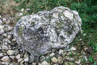 Büyük yaşlı taş küçük taşların üzerinde ve yeşil çimlerin üzerinde