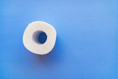 Mavi arka planda izole edilmiş beyaz bir tuvalet kağıdı rulosu..