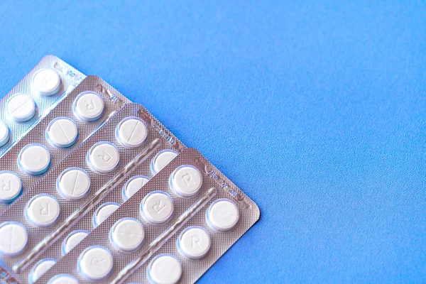 Aspirina en una ampolla en la parte superior. Pastillas de vitamina C en un paquete. Comprimidos blancos en blíster sobre fondo azul de primer plano con enfoque suave . — Foto de Stock