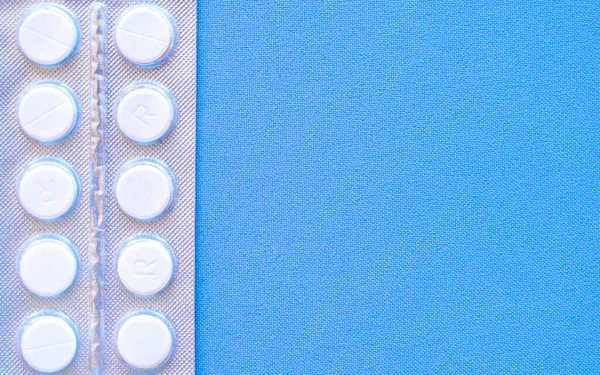 Aspirina en una ampolla en la parte superior. Pastillas de vitamina C en un paquete. Comprimidos blancos en blíster sobre fondo azul de primer plano con enfoque suave . — Foto de Stock