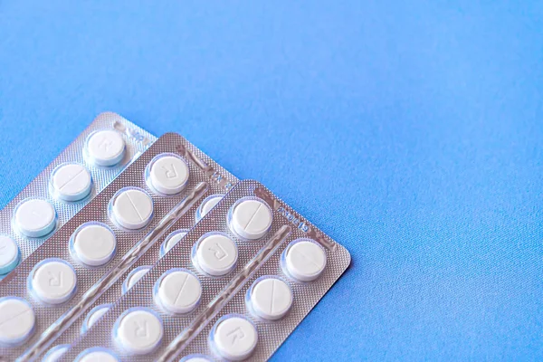 Aspirina en una ampolla en la parte superior. Pastillas de vitamina C en un paquete. Comprimidos blancos en blíster sobre fondo azul de primer plano con enfoque suave . — Foto de Stock