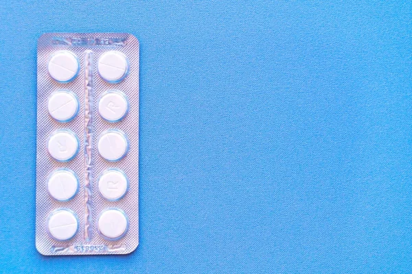 Aspirina en una ampolla en la parte superior. Pastillas de vitamina C en un paquete. Comprimidos blancos en blíster sobre fondo azul de primer plano con enfoque suave . — Foto de Stock
