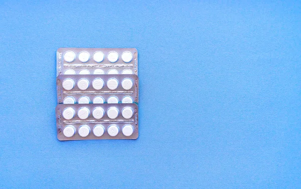 Aspirin in a blister on top. Vitamin C pills in a pack. White tablets in a blister on a blue background close-up with soft focus. — Stock Photo, Image