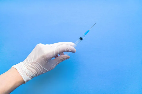 코로나 바이러스 백신을 포함하는 주사기는 흰색 장갑을 낀 손에 의해 파란색 배경에 가까이 붙어 있다. 원문을 위한 공간. — 스톡 사진