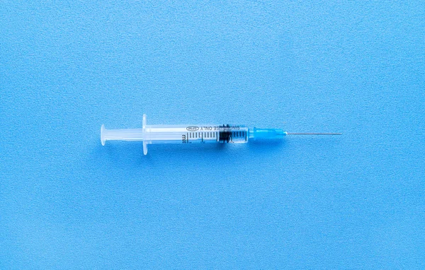 Шприц с коронавирусной вакциной, выделенный на синем фоне с пространством для текстового крупного плана . — стоковое фото