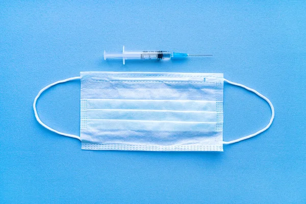 코로나 바이러스 백신 이 장착 된 주사기와 파란색 배경 위의 의료용 붕대. — 스톡 사진